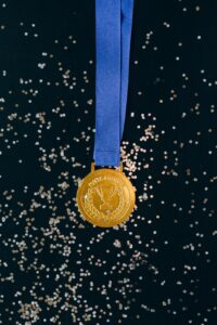 Gold winner medal with blue ribbon on black confetti background.